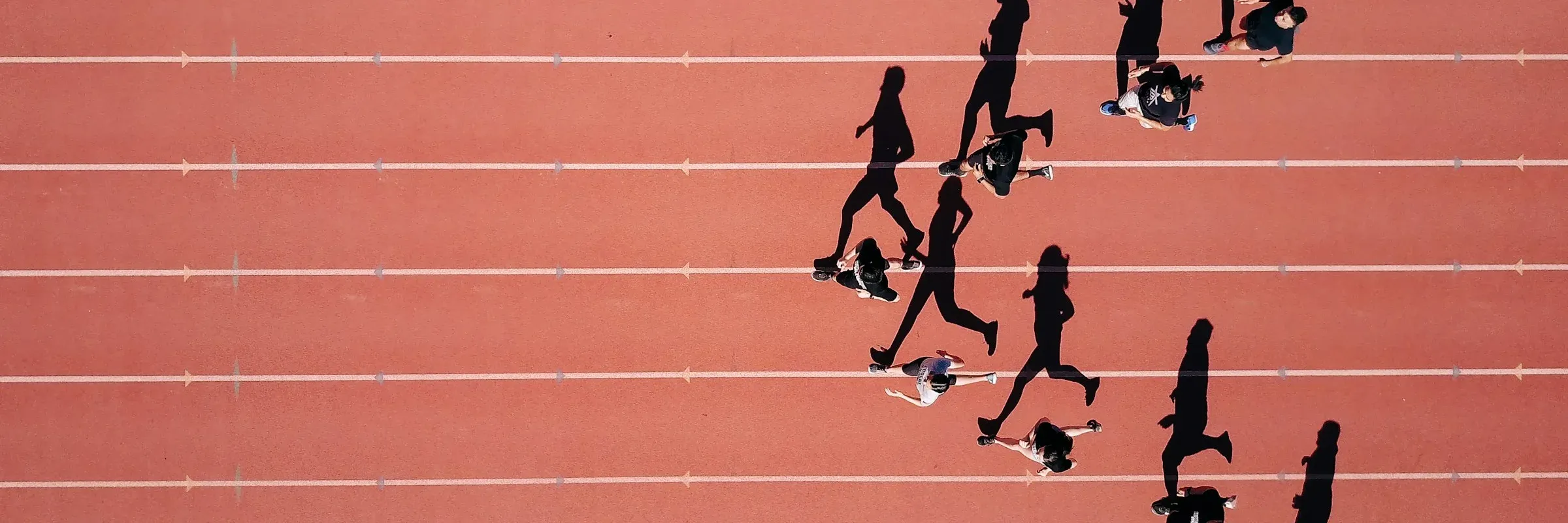 Vista cenital de un grupo corriendo en una pista de atletismo